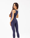 Woman wearing a dark blue sleeveless top and leggings on a white background