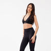Woman wearing a black sports bra and leggings set on a white background